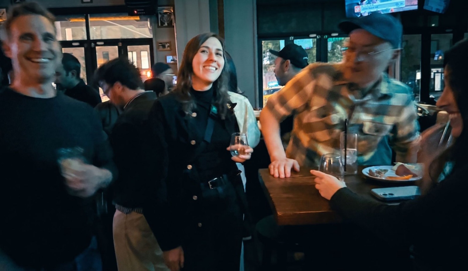 Attendees laughing and talking around a high-top table at a bar