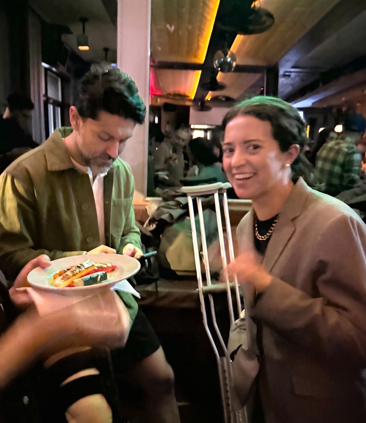 Two attendees with plates of food, one smiling at the camera